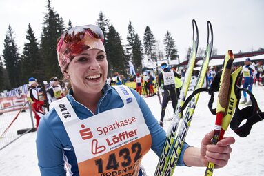 Ein Frau mit Langlaufskiern und Stöcken in der Hand lacht in die Kamera | © Bodenmais Tourismus & Marketing GmbH